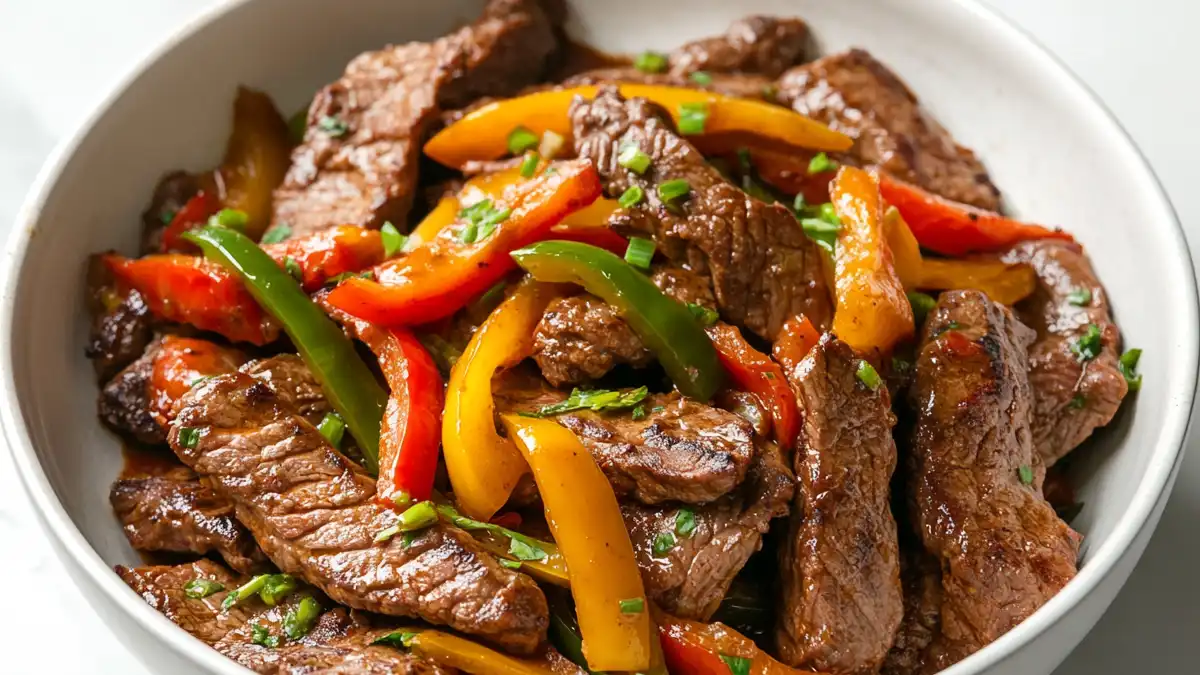 Low FODMAP Slow Cooker Steak and Peppers with red, yellow, and green bell peppers in a white bowl
